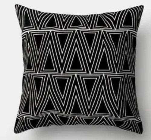 A black square throw pillow with a repeating pattern of white lined triangles to create s geometric design.