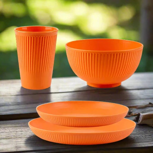 An orange wheat straw dinnerware set. The set includes one large plate, one small plate, one bowl and one cup.