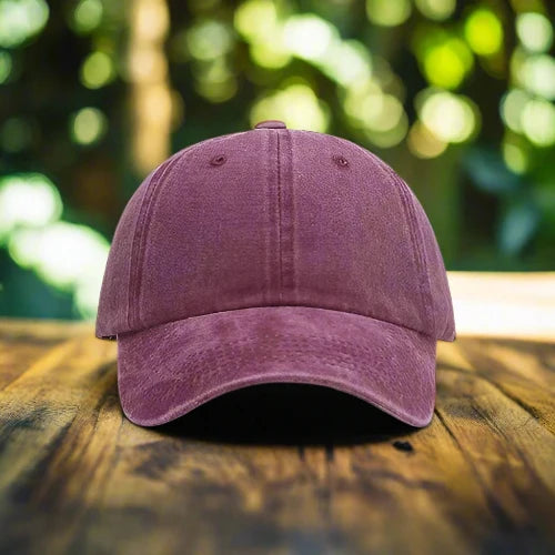 A wine-red stone washed baseball cap in the natural beauty of the outdoors.