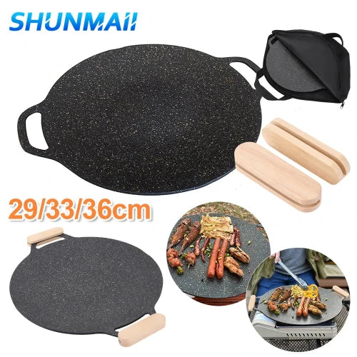 A circular non stick black speckled griddle/ grill pan with raised edges, removable wooden handles, and a carrying case. It is shown in use with various grilled foods like meat and vegetables