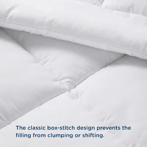 A close up of a fluffy white duvet insert/comforter with the top folded down and text that says, "The classic box-stitch design prevents the filling from clumping or shifting."