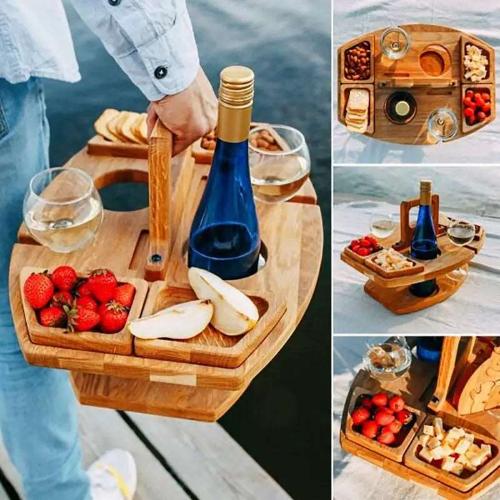 Four different angles of a portable wooden picnic table/tray with a handle. There are two wine glasses in holders, a blue wine bottle in a holder and sectioned pieces for snacks. In one picture a person is holding the table by its handle showcasing its portability.