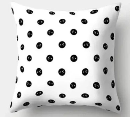 A white throw pillow with black polka dots. Inside the polka dots are four small white dots. 