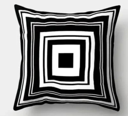 A white square throw pillow with a geometric pattern of black concentric squares.