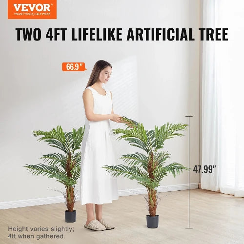 This picture is taken inside a home. The VEVOR Logo is on the top left-hand side and has the header, "Two 4ft lifelike artificial tree" There is a tree on either side of a woman. There is a text box next to the woman that says, "66.9"." There is a dimension next to the tree that says "47.99"." and at the bottom of the picture is an announcement. "Height varies slightly; 4 ft when gathered" 