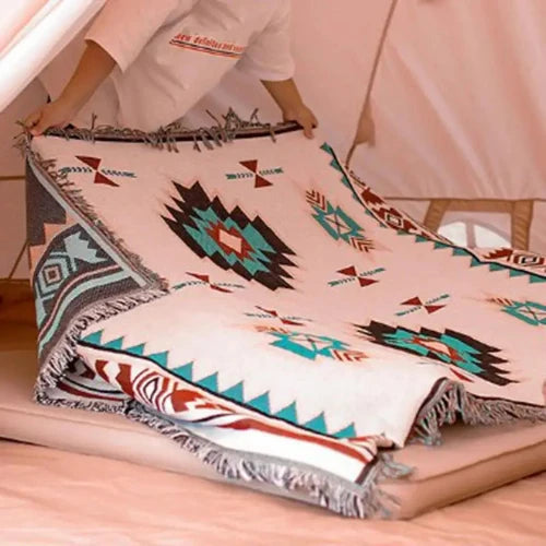 A person is opening and laying a white floor mat with a southwestern design on the floor of a yurt.